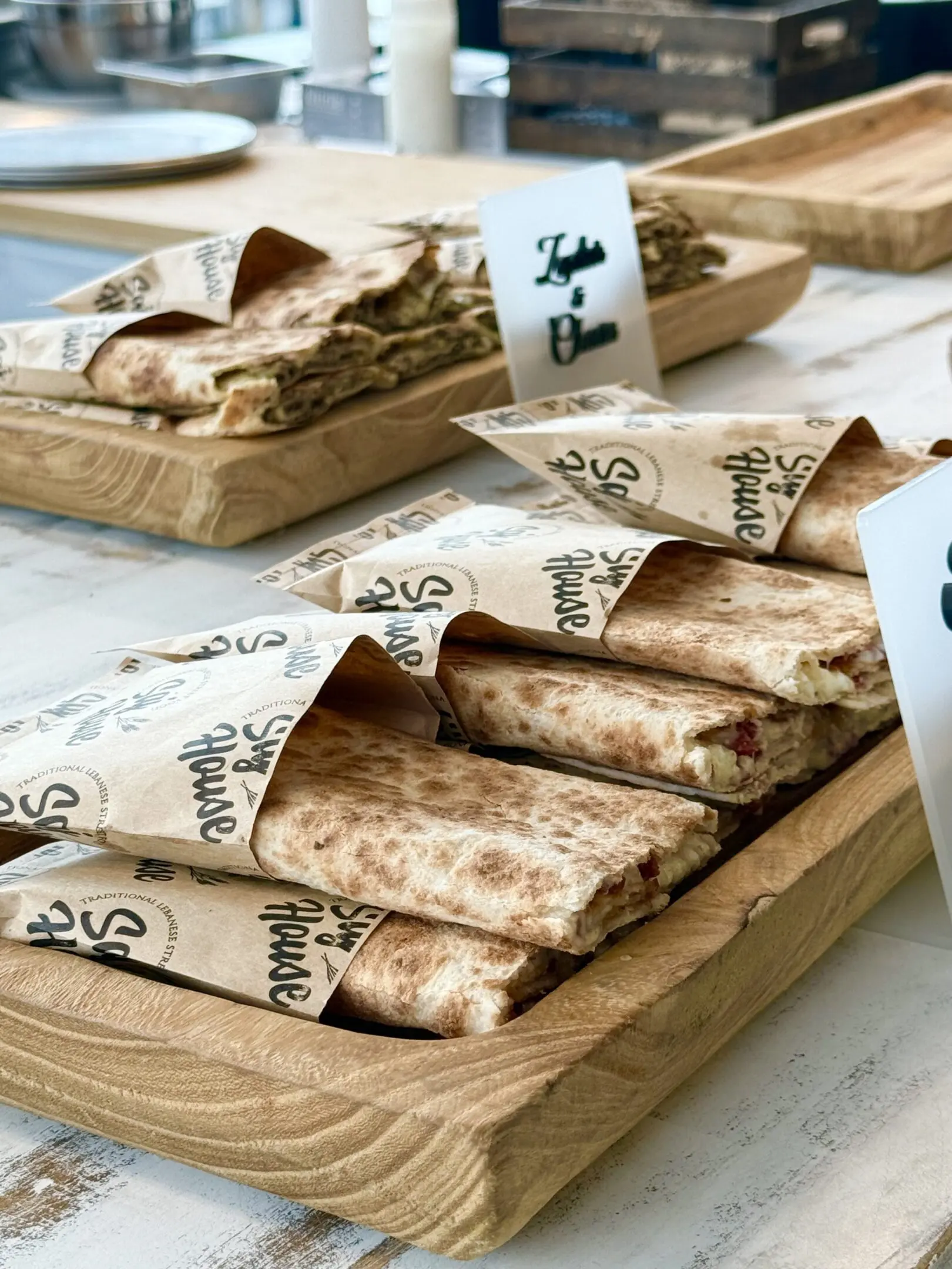 Traditional flatbreads wrapped in patterned paper on wooden trays.