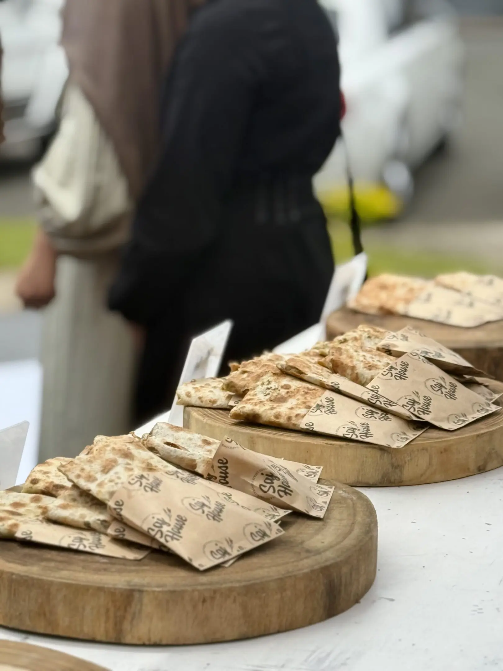 Close-up of flatbreads stacked on wooden boards at a market stall.