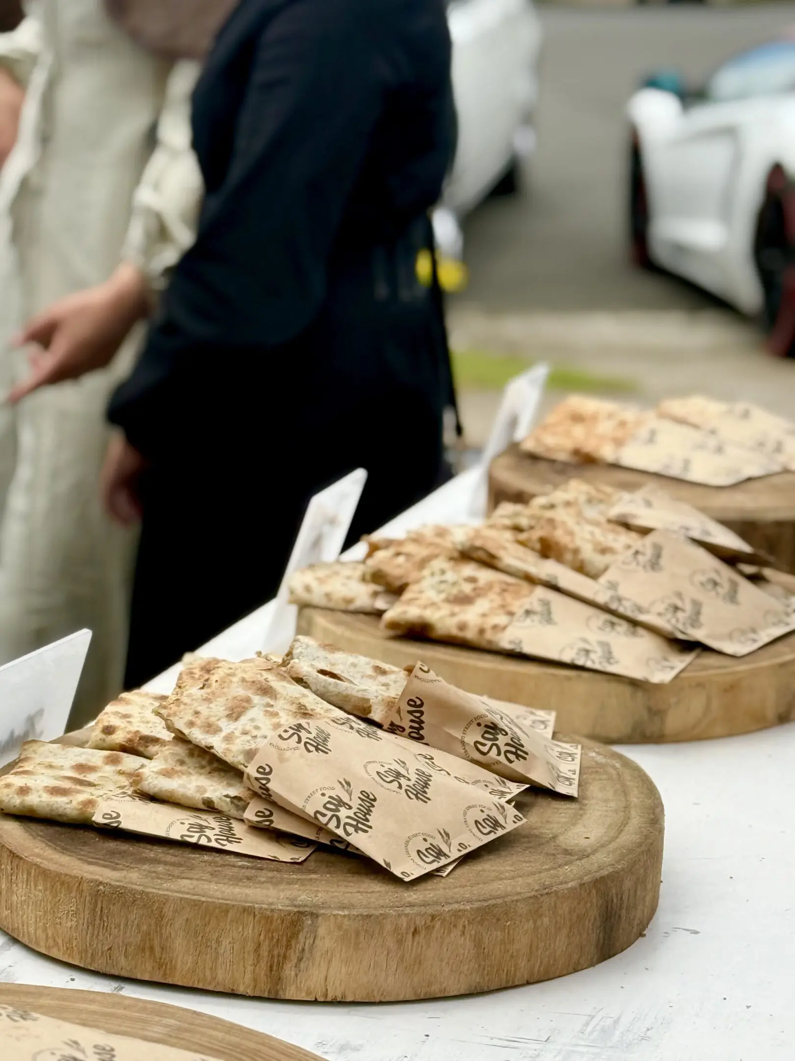 Wood-fired flatbread slices on wooden boards with handwritten labels.