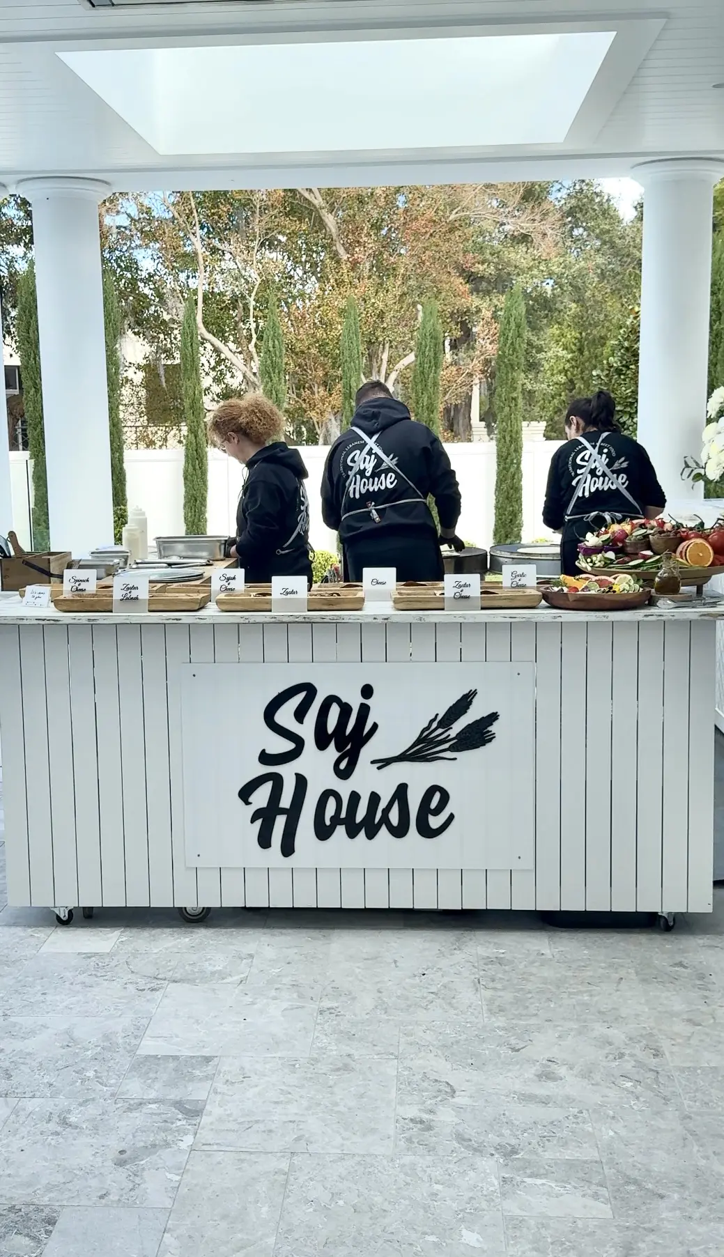 Three people preparing food behind a stand labeled 'Sogi House'.