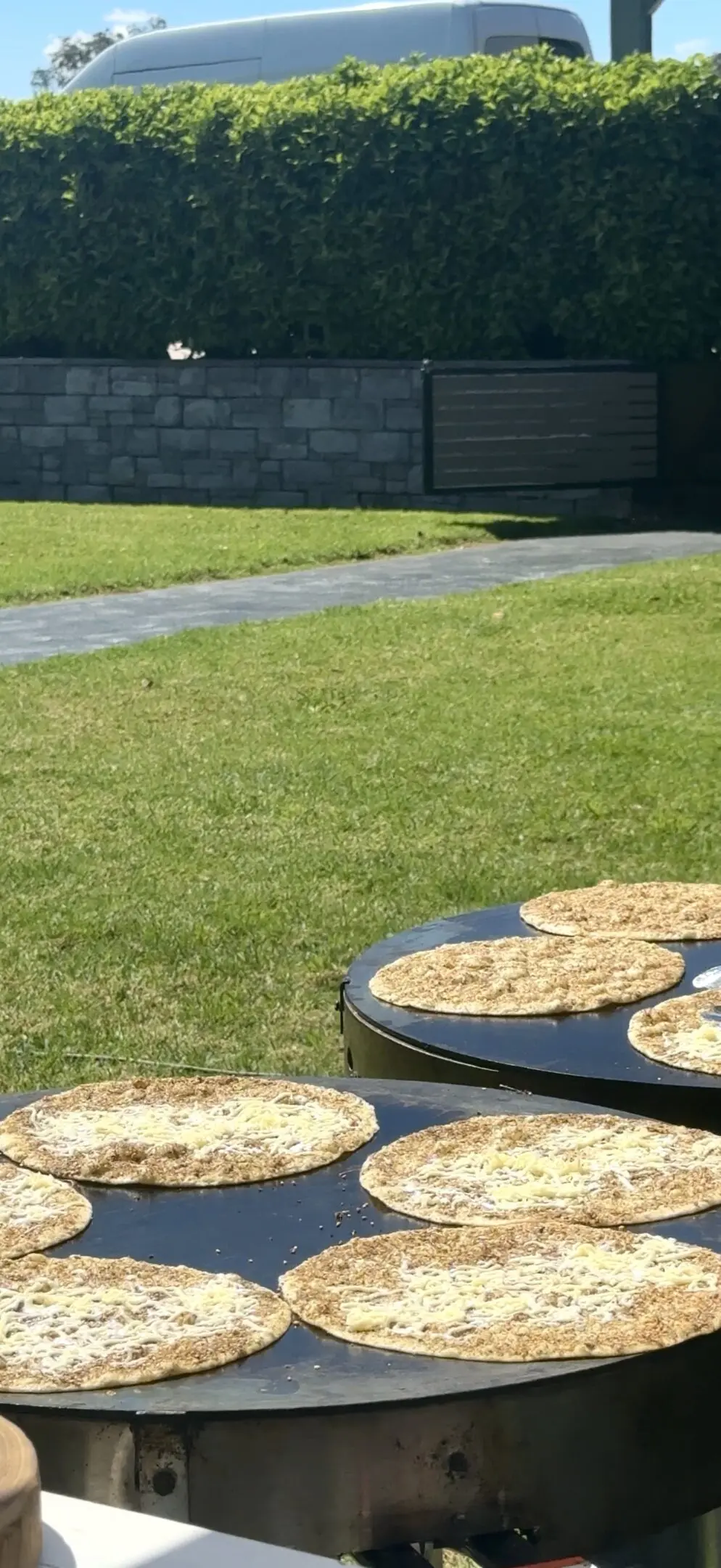 Pies cooling on trays outdoors on a sunny day.