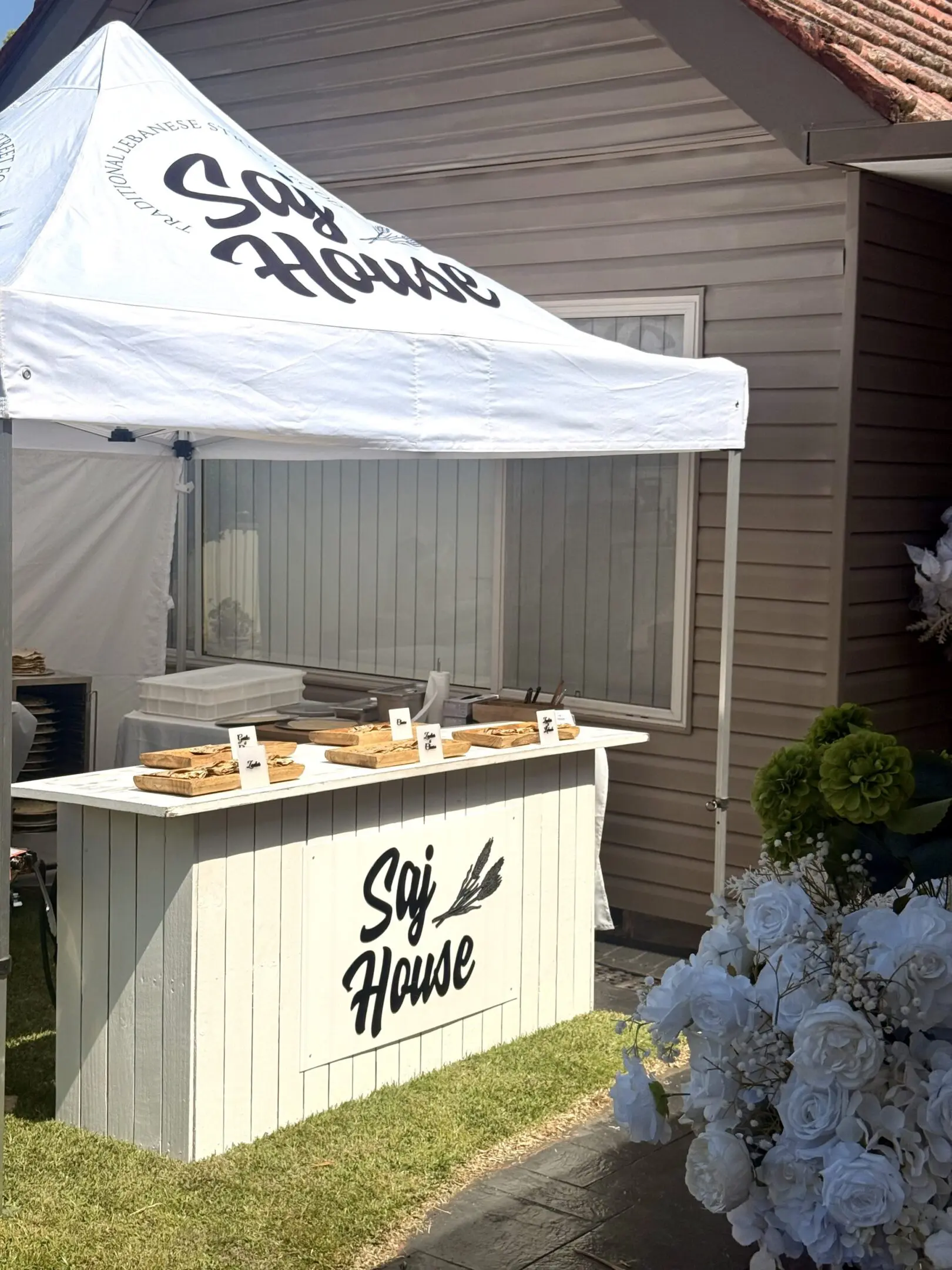 A small wooden stall under a white tent labeled 'Ski House' with items on display.