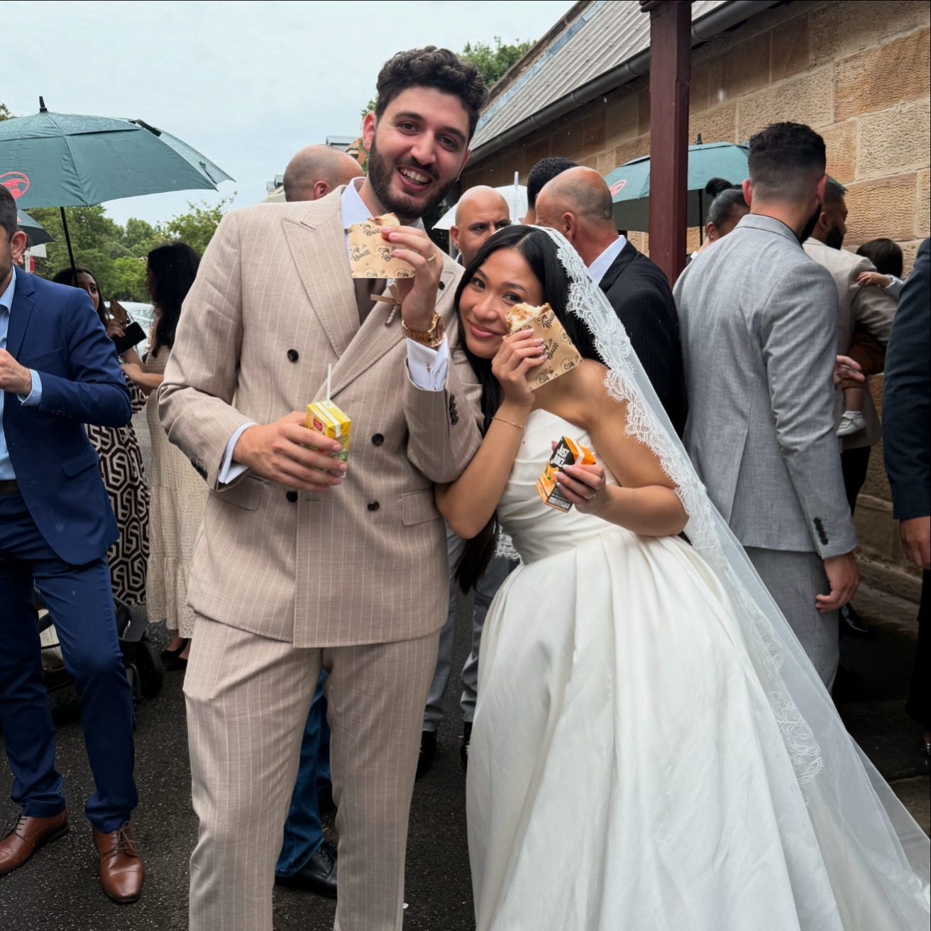 Happy couple celebrating their wedding day with friends outdoors.