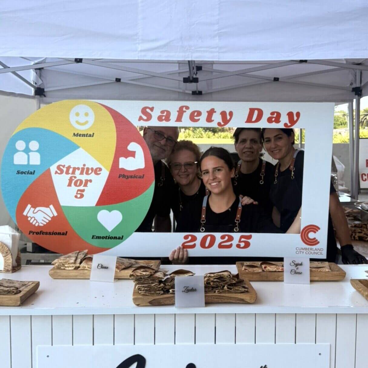 Group of people celebrating Safety Day 2023 with a colorful wheel.
