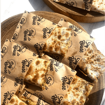 Grilled quesadillas served on branded parchment paper.